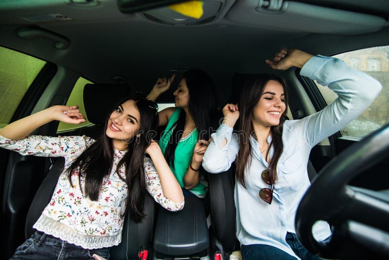 Tres muchachas jovenes de la belleza que conducen en un baile del coche y que se divierten en calle de la ciudad fotos de archivo libres de regalías Tres muchachas jovenes de la belleza que conducen en un baile del coche y que se divierten en calle de la ciudad fotos de archivo libres de regalías