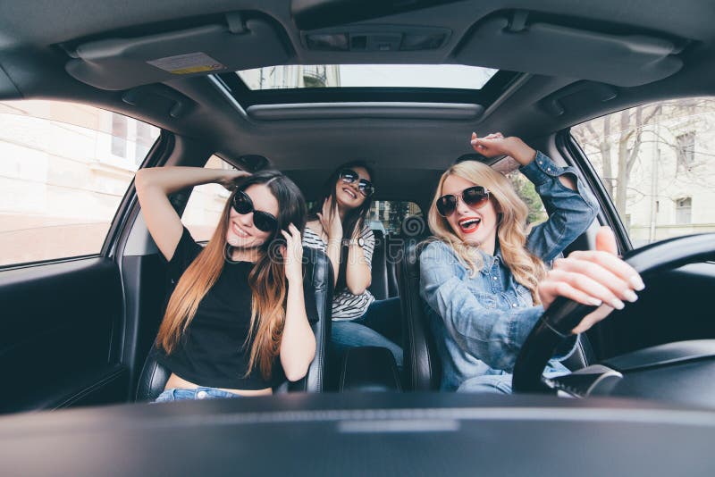 Tres muchachas que conducen en un coche convertible y que se divierten, escuchan música y bailan fotos de archivo