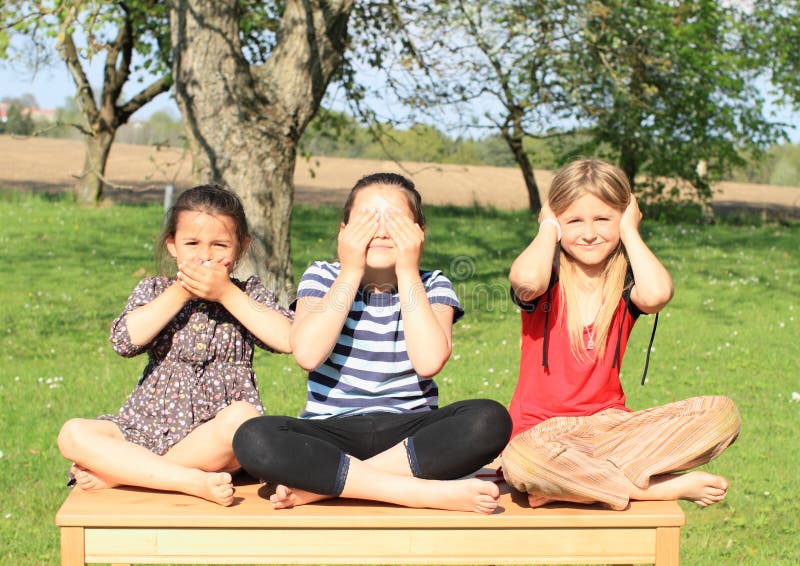 Tres muchachas sonrientes que se sientan en la tabla foto de archivo libre de regalías Tres muchachas sonrientes que se sientan en la tabla foto de archivo libre de regalías