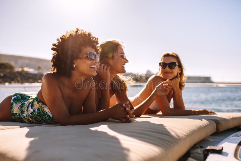 Tres mujeres jovenes que toman el sol en el yate foto de archivo libre de regalías Tres mujeres jovenes que toman el sol en el yate foto de archivo libre de regalías
