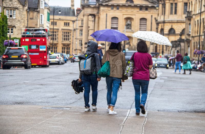 Tres mujeres que se van con los paraguas y los bolsos en un día lluvioso en Oxford Inglaterra foto de archivo libre de regalías Tres mujeres que se van con los paraguas y los bolsos en un día lluvioso en Oxford Inglaterra foto de archivo libre de regalías