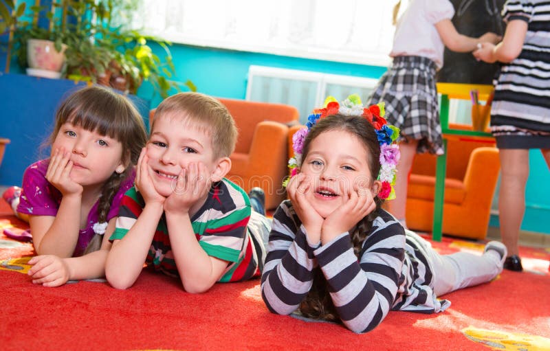 Three cute preschoolers lying on floor with hands under cheeks. Three cute preschoolers lying on floor with hands under cheeks