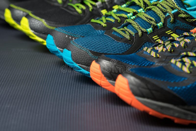 Three pairs of colorful running trainers / exercise shoes on the floor of a sport / shoe shop. Potential copy space on floor. Three pairs of colorful running trainers / exercise shoes on the floor of a sport / shoe shop. Potential copy space on floor.