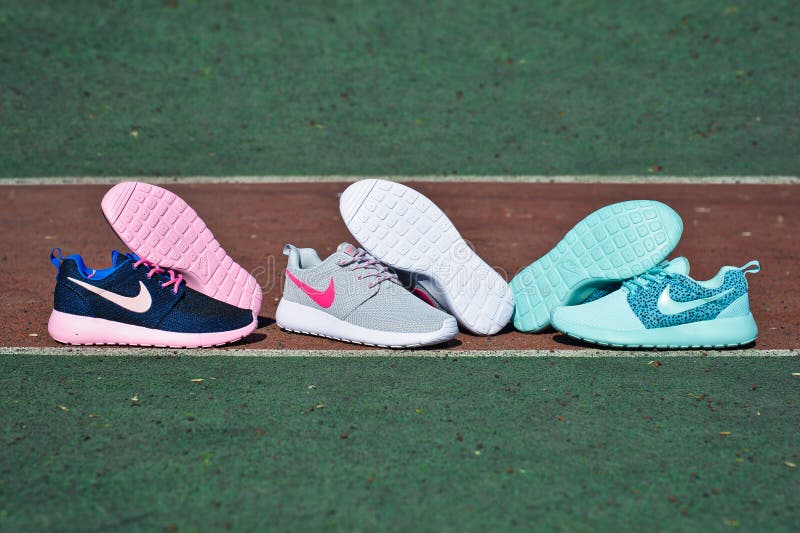 Three pairs of Nike Roshe Run sneakers, running shoes, trainers close up view, shot outdoors on sports field background. Sport and casual footwear concept. Krasnoyarsk, Russia - April 6, 2015. Three pairs of Nike Roshe Run sneakers, running shoes, trainers close up view, shot outdoors on sports field background. Sport and casual footwear concept. Krasnoyarsk, Russia - April 6, 2015