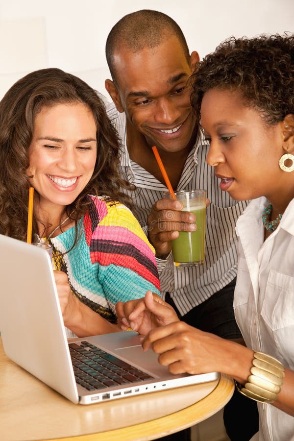 Tres personas que cenan hacia fuera usando una computadora portátil fotografía de archivo libre de regalías Tres personas que cenan hacia fuera usando una computadora portátil fotografía de archivo libre de regalías