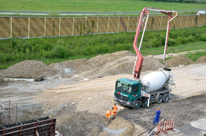 Tres trabajadores y camión concreto del transporte con la bomba concreta de manera operacional Esta actividad se relaciona con la fotografía de archivo libre de regalías Tres trabajadores y camión concreto del transporte con la bomba concreta de manera operacional Esta actividad se relaciona con la fotografía de archivo libre de regalías