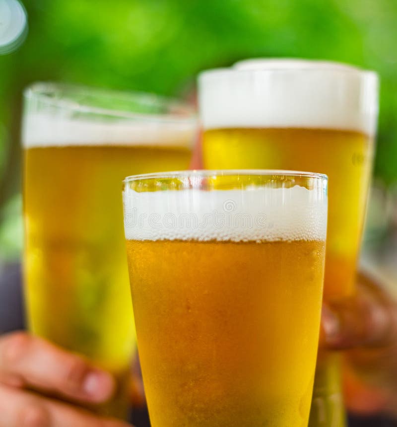 Tres vasos de cerveza a disposición Vidrios de cerveza que tintinean en la barra o el pub al aire libre imágenes de archivo libres de regalías Tres vasos de cerveza a disposición Vidrios de cerveza que tintinean en la barra o el pub al aire libre imágenes de archivo libres de regalías