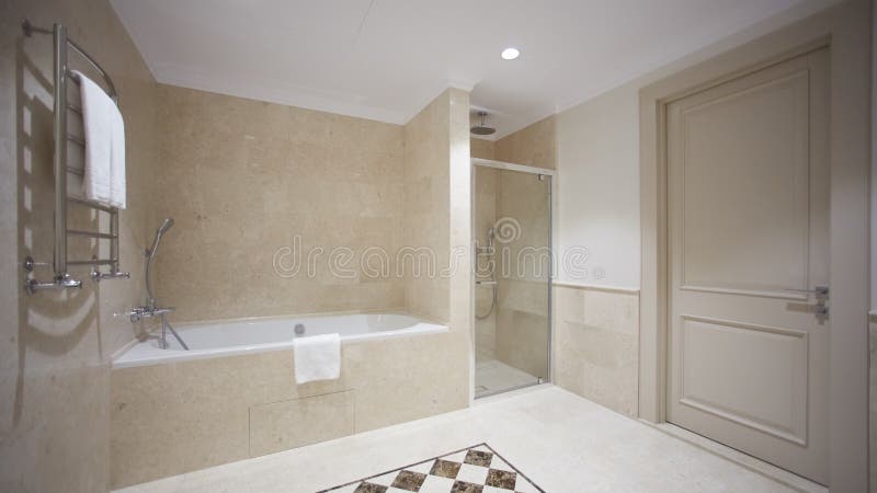 Trevligt badrum i en modern stil med gråa belade med tegel väggar Det finns ett vitt bad med en exponeringsglasdelning, dusch, av royaltyfri foto Trevligt badrum i en modern stil med gråa belade med tegel väggar Det finns ett vitt bad med en exponeringsglasdelning, dusch, av royaltyfri foto