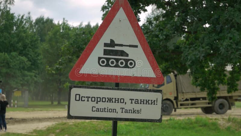 Triangolo del segnale di pericolo in rosso, contro la colonna militare di passaggio traduzione Cautela, carri armati!