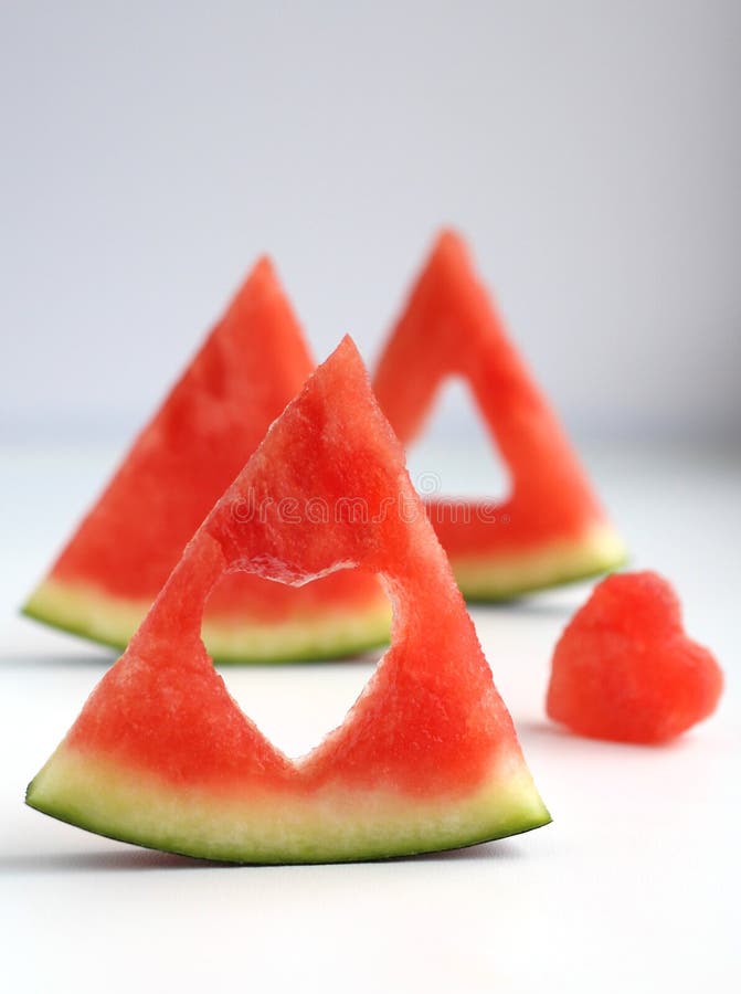 Triangular pieces of watermelon with a heart cut from the pulp of watermelon in a cup on a light background. High quality photo. Triangular cut watermelon stock images, royalty-free photos and pictures