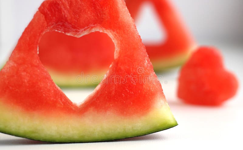 Triangular pieces of watermelon with a heart cut from the pulp of watermelon in a cup on a light background. High quality photo. Triangular cut watermelon stock images, royalty-free photos and pictures
