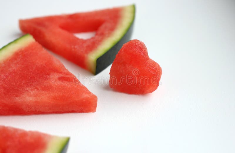 Triangular pieces of watermelon with a heart cut from the pulp of watermelon in a cup on a light background. High quality photo. Triangular cut watermelon stock images, royalty-free photos and pictures