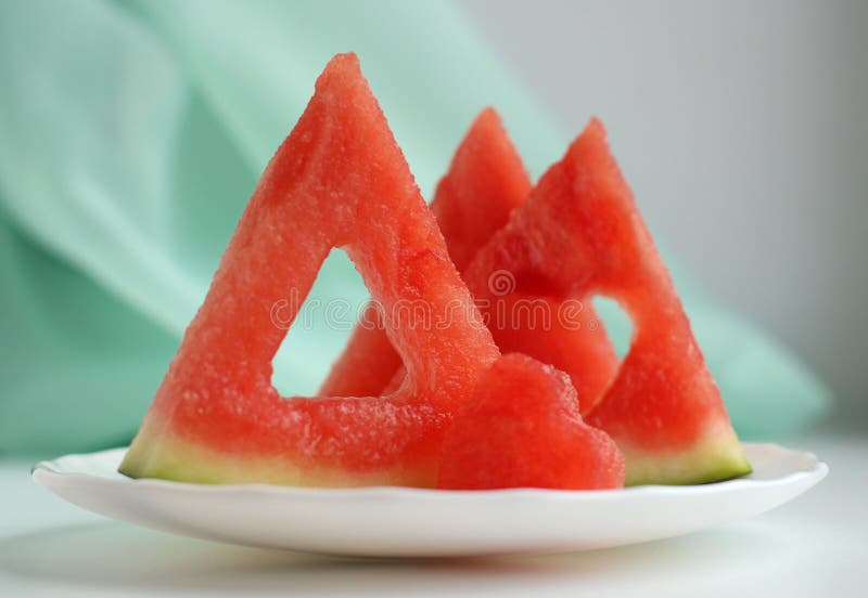 Triangular pieces of watermelon with a heart cut from the pulp of watermelon in a cup on a light background. High quality photo. Triangular cut watermelon stock images, royalty-free photos and pictures