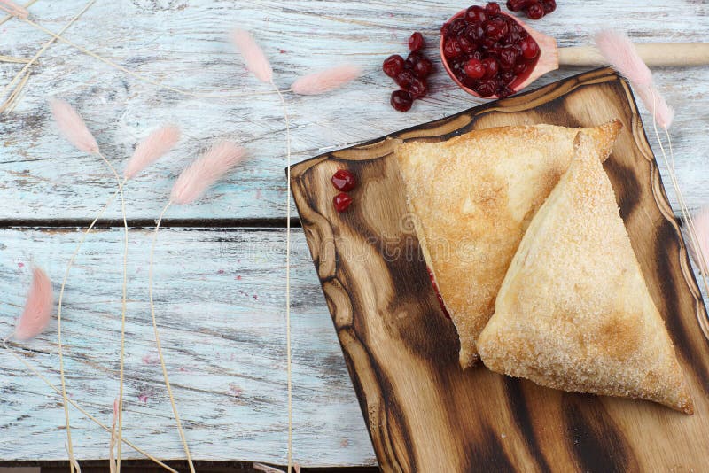 Triangular pies on a board and a spoon with cranberries, top view royalty free stock photo