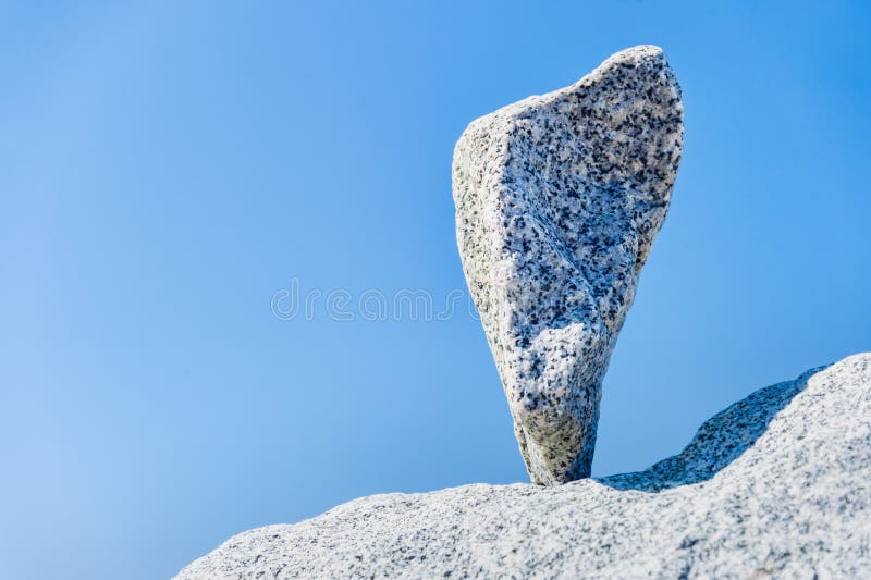 Triangular rock balanced on the tip in Vancouver rock stacking garden