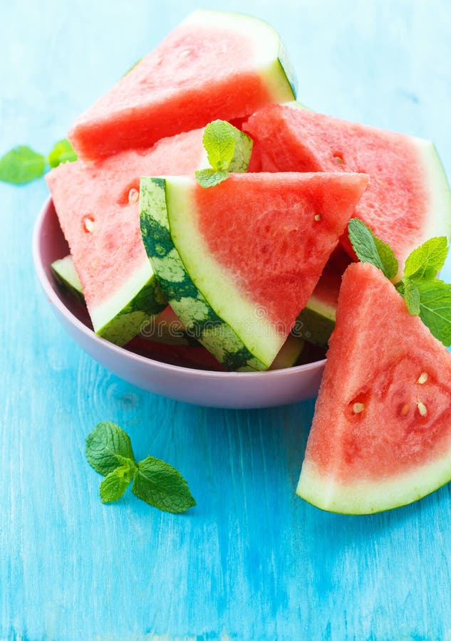 Triangular slices of fresh watermelon with mint on blue wooden background. Triangular cut watermelon stock images, royalty-free photos and pictures