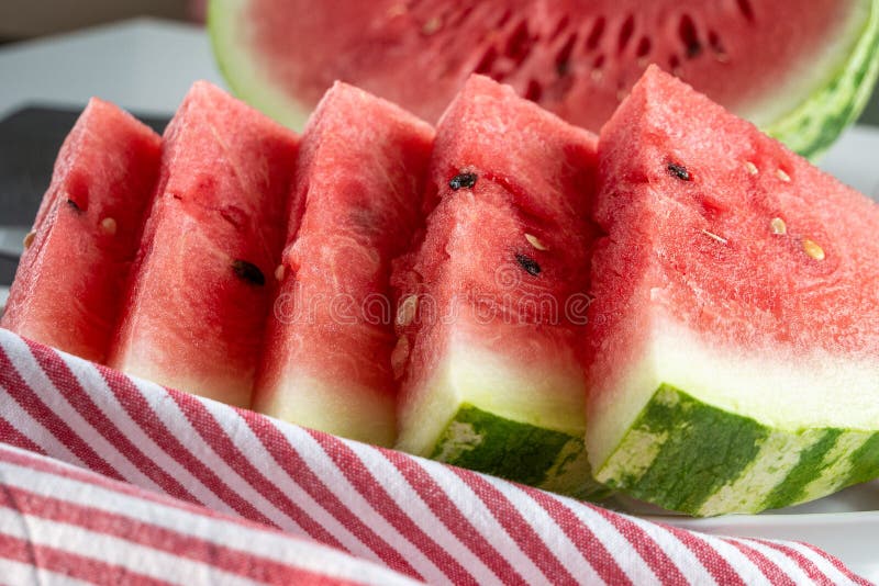 Close up of triangular slices of ripe watermelon with red flesh served with striped napkin. Triangular cut watermelon stock images, royalty-free photos and pictures