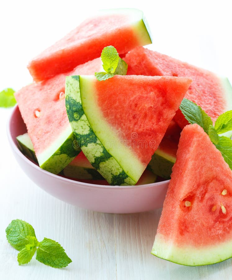 Triangular slices of fresh watermelon with mint on white wooden background. Triangular cut watermelon stock images, royalty-free photos and pictures