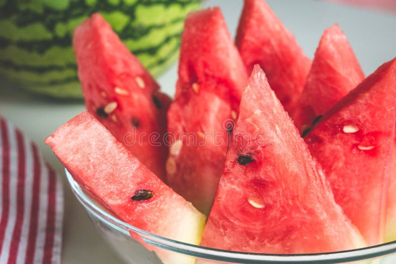 Triangular slices of ripe watermelon with red flesh and black seeds served on plate. Triangular cut watermelon stock images, royalty-free photos and pictures