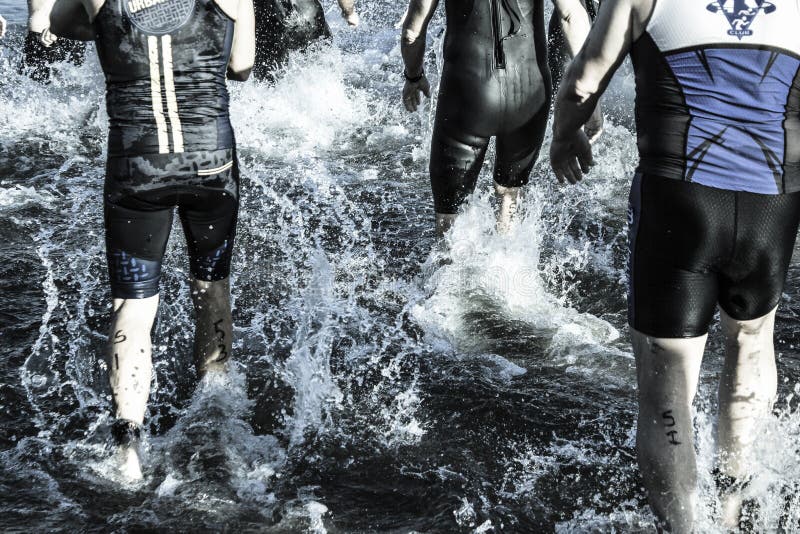 Triathletes Run into a Lake at the Beginning of a Race Stock Photo