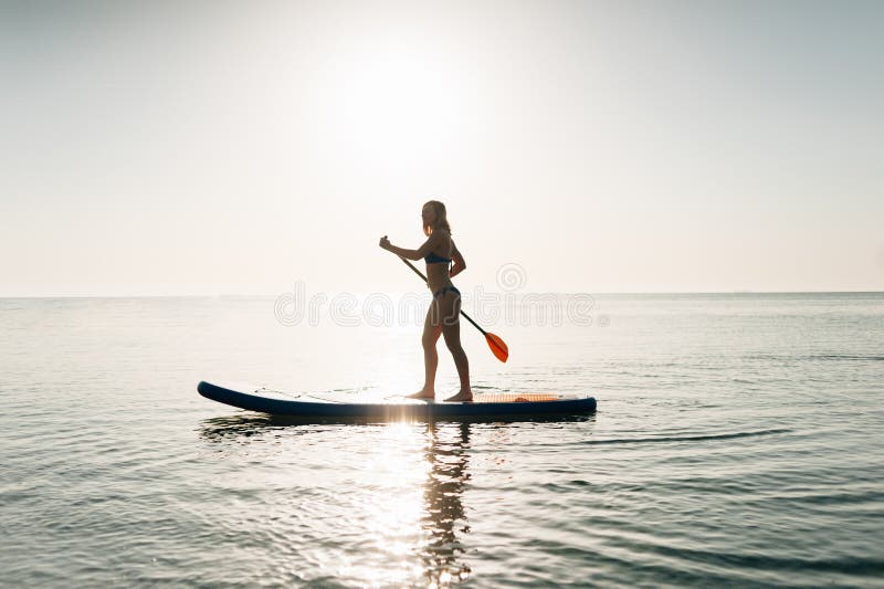 Tribune op de vrouw van de peddelraad het paddleboarding op Hawaï die zich gelukkig op paddleboard op blauw water bevinden stock foto's Tribune op de vrouw van de peddelraad het paddleboarding op Hawaï die zich gelukkig op paddleboard op blauw water bevinden stock foto's