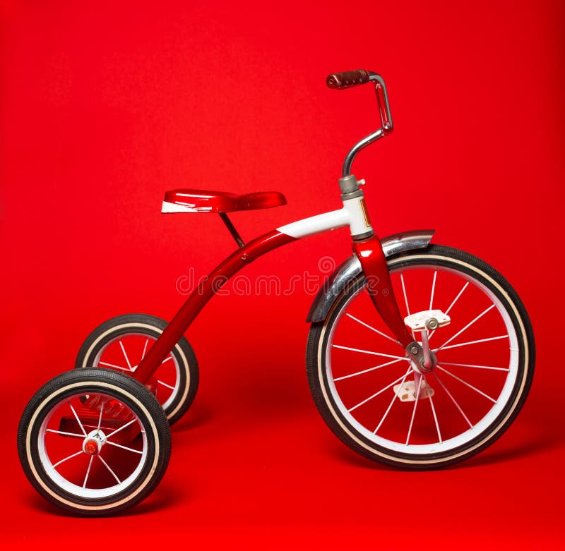 Triciclo rojo del vintage en un fondo rojo brillante fotografía de archivo Triciclo rojo del vintage en un fondo rojo brillante fotografía de archivo