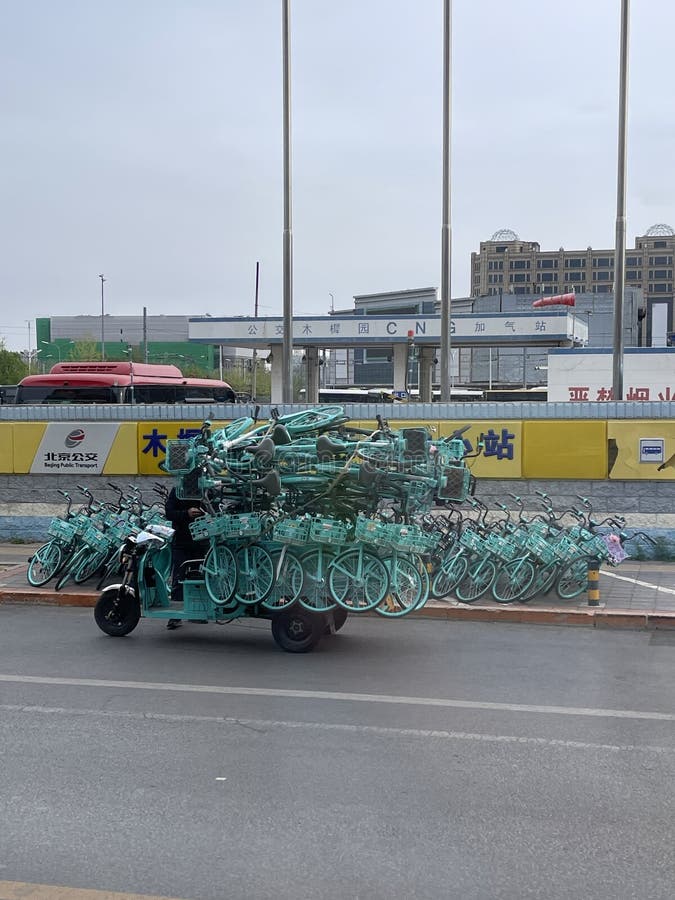 Triciclo sobrecarregado transportando bicicletas compartilhadas em uma rua da cidade foto de stock