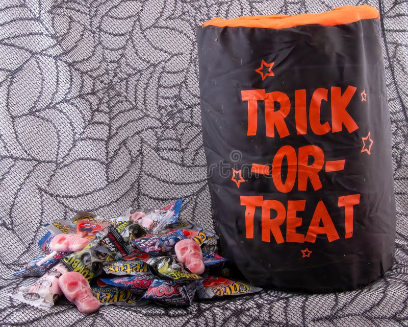 Trick Or Treat Candy Bag with pile of Halloween sweets on a spider web background. Trick Or Treat Candy Bag with pile of Halloween sweets on a spider web background