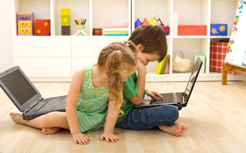 Kids busy using the computer sitting on the floor in their room. Kids busy using the computer sitting on the floor in their room