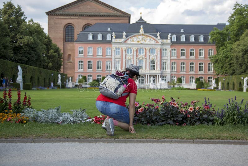 A woman examines flowers in a flowerbed in front of the Prince-elector Palace in the center of Trier royalty free stock images A woman examines flowers in a flowerbed in front of the Prince-elector Palace in the center of Trier royalty free stock images