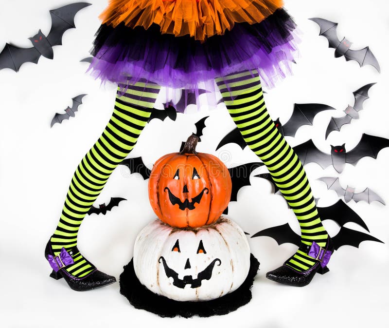 Trik o ossequio Bambini di Halloween Gambe a strisce di piccola ragazza della strega con le zucche sorridente felici fotografia stock libera da diritti Trik o ossequio Bambini di Halloween Gambe a strisce di piccola ragazza della strega con le zucche sorridente felici fotografia stock libera da diritti