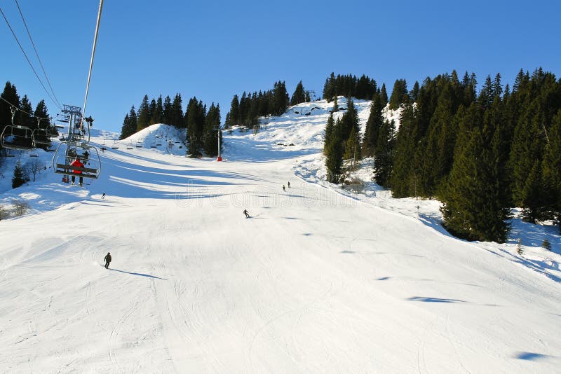 Trilhas do elevador e do esqui de esqui em montanhas dos cumes da neve imagem de stock Trilhas do elevador e do esqui de esqui em montanhas dos cumes da neve imagem de stock