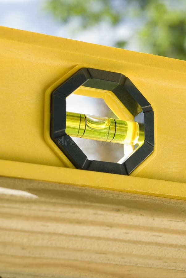 A yellow plastic builders level sits on top of a railing. A yellow plastic builders level sits on top of a railing