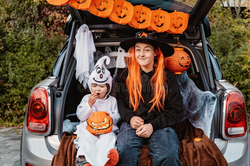 Trincea. tronco o tratta. Bambini felici in costumi festeggiano la festa di halloween mangiando caramelle in un bagagliaio decorat