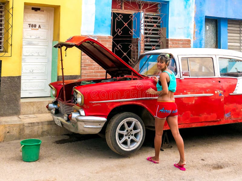 Trinidad, Cuba Juni 2016: Vrouw het bevestigen auto Lokale jonge vrouw die een oude uitstekende kat herstellen stock afbeeldingen Trinidad, Cuba Juni 2016: Vrouw het bevestigen auto Lokale jonge vrouw die een oude uitstekende kat herstellen stock afbeeldingen