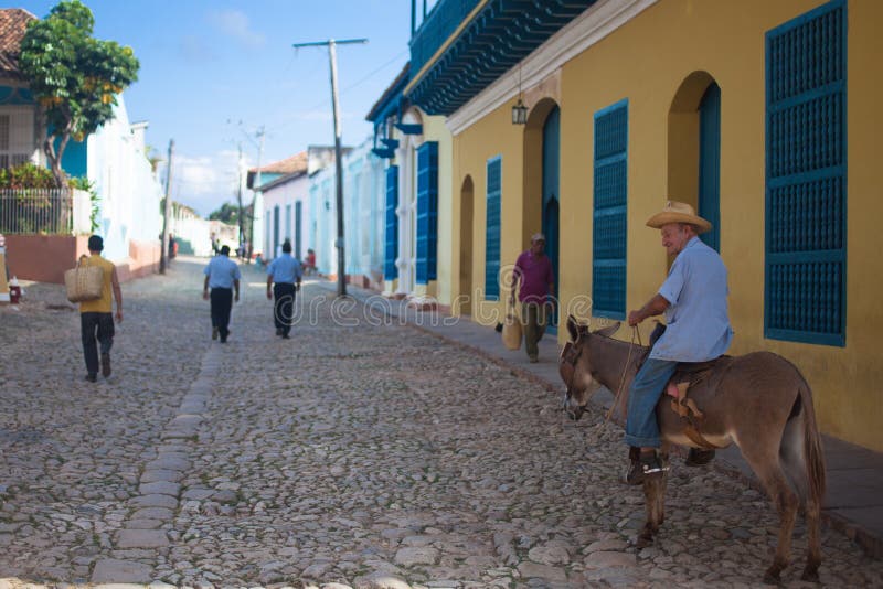 TRINIDAD, CUBA - NOVEMBER 9, 2012: Old man in the hat riding a donkey on street stock photos TRINIDAD, CUBA - NOVEMBER 9, 2012: Old man in the hat riding a donkey on street stock photos