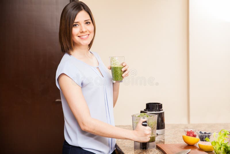 Beautiful young Hispanic woman drinking a glass freshly made healthy juice at home. Beautiful young Hispanic woman drinking a glass freshly made healthy juice at home