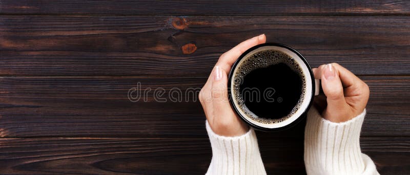 Trinkender Kaffee der einsamen Frau morgens, Draufsicht von den weiblichen Händen, die Schale des Heißgetränks auf hölzernem Schr