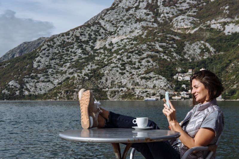 Trinkender Kaffee der jungen Frau und mit smarphone morgens a stockfotografie Trinkender Kaffee der jungen Frau und mit smarphone morgens a stockfotografie