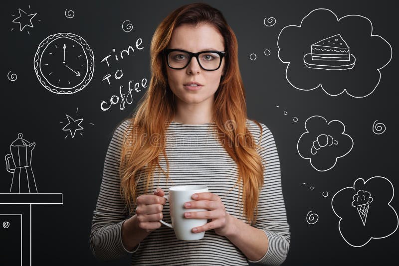 Coffee time. Young calm beautiful student standing with a cup of hot tasty coffee and looking thoughtful while trying to choose a dessert in a cafe. Coffee time. Young calm beautiful student standing with a cup of hot tasty coffee and looking thoughtful while trying to choose a dessert in a cafe