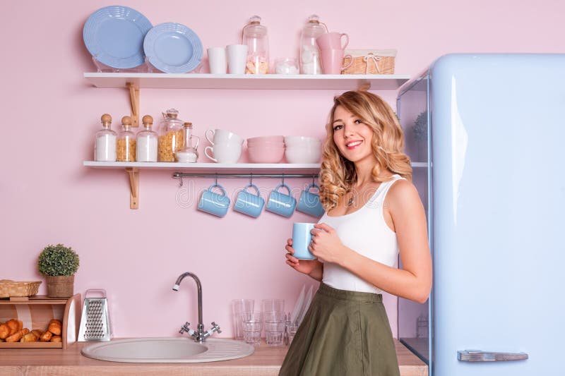 Trinkender Kaffee oder Tee der jungen glücklichen Frau zu Hause in der Küche Blondes schönes Mädchen, das ihr Frühstück bevor dem stockbild Trinkender Kaffee oder Tee der jungen glücklichen Frau zu Hause in der Küche Blondes schönes Mädchen, das ihr Frühstück bevor dem stockbild