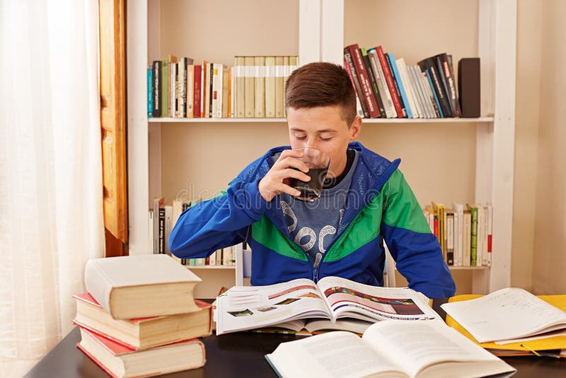 Trinkender Koks des männlichen Jugendlichen beim Studieren