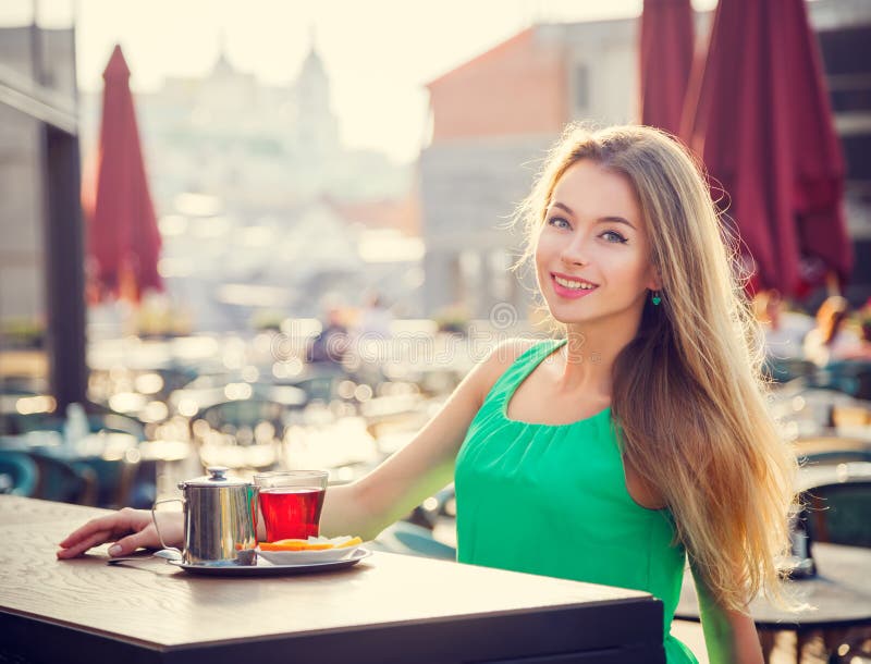 Trinkender Tee der jungen Frau in einem Kaffee draußen stockbilder Trinkender Tee der jungen Frau in einem Kaffee draußen stockbilder