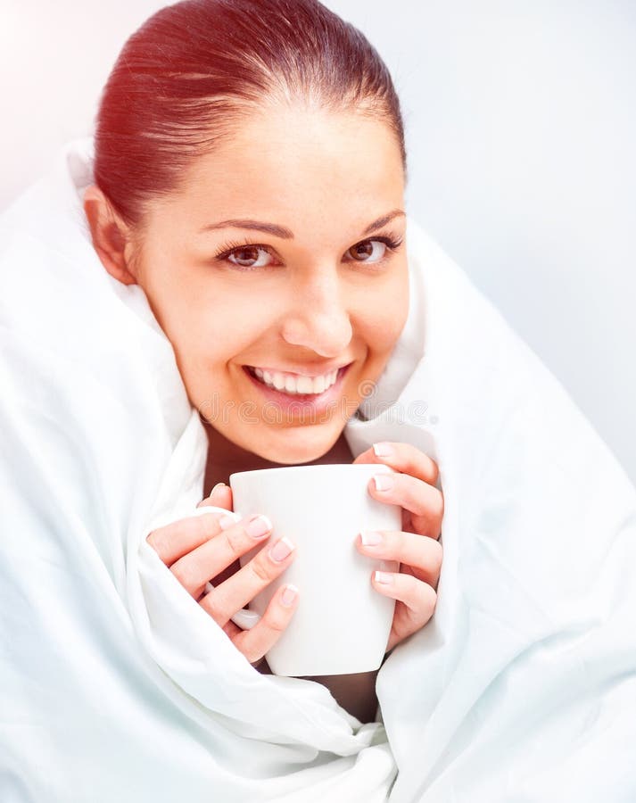 Beautiful young woman drinking tea in bed at home. Beautiful young woman drinking tea in bed at home