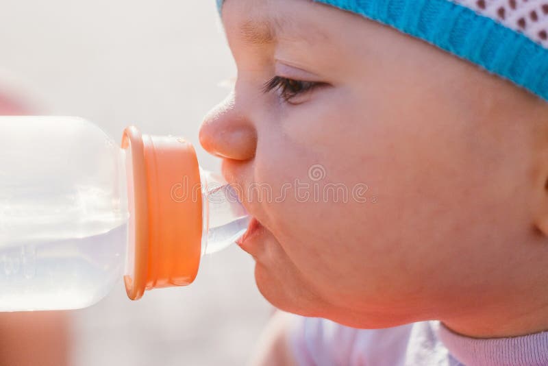 Trinkwasser des Babys von einer Babyflasche für einen Weg stockbilder Trinkwasser des Babys von einer Babyflasche für einen Weg stockbilder
