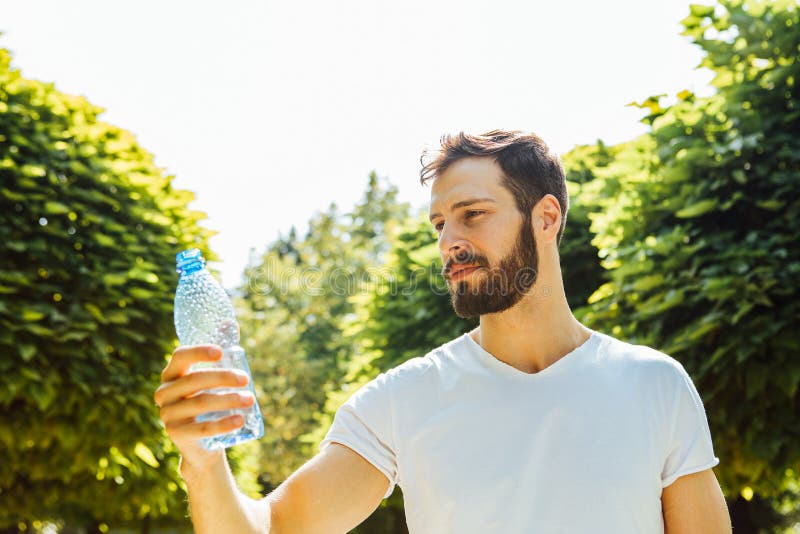 Trinkwasser des erwachsenen Mannes von einer Flasche draußen lizenzfreie stockbilder Trinkwasser des erwachsenen Mannes von einer Flasche draußen lizenzfreie stockbilder