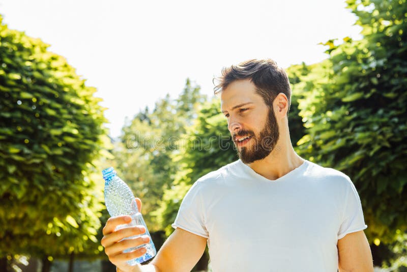 Trinkwasser des erwachsenen Mannes von einer Flasche draußen stockfoto Trinkwasser des erwachsenen Mannes von einer Flasche draußen stockfoto