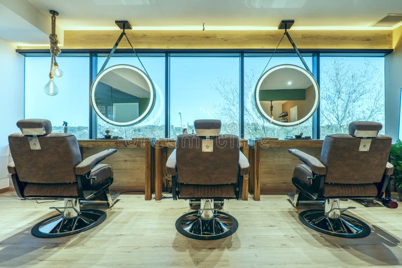 Trio of armchairs for a beauty salon with brown upholstery and circular mirrors with leds and chestnut wood floors