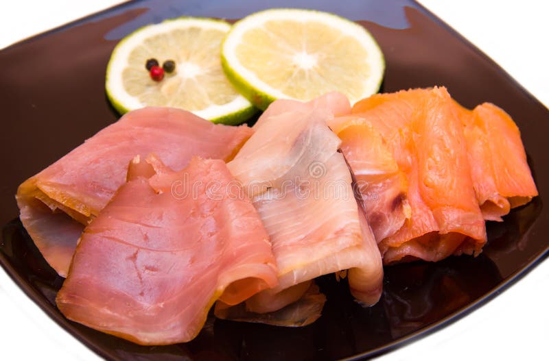 Trio of smoked fish on plate on white background seen close. Trio of smoked fish on plate on white background seen close