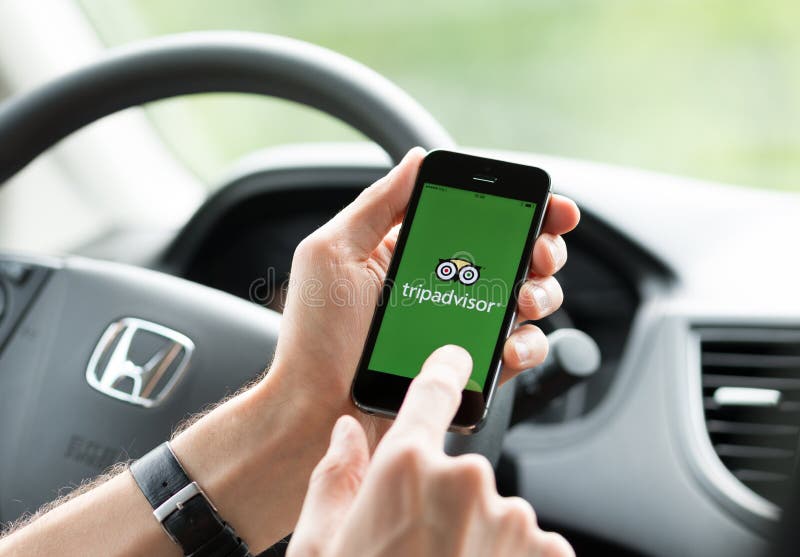 KIEV, UKRAINE - MAY 16, 2014: Man in a car planning a trip using Tripadvisor app on Apple iPhone 5S. Tripadvisor is a travel guide source providing reviews, photos and advice for hotels and vacations. KIEV, UKRAINE - MAY 16, 2014: Man in a car planning a trip using Tripadvisor app on Apple iPhone 5S. Tripadvisor is a travel guide source providing reviews, photos and advice for hotels and vacations.